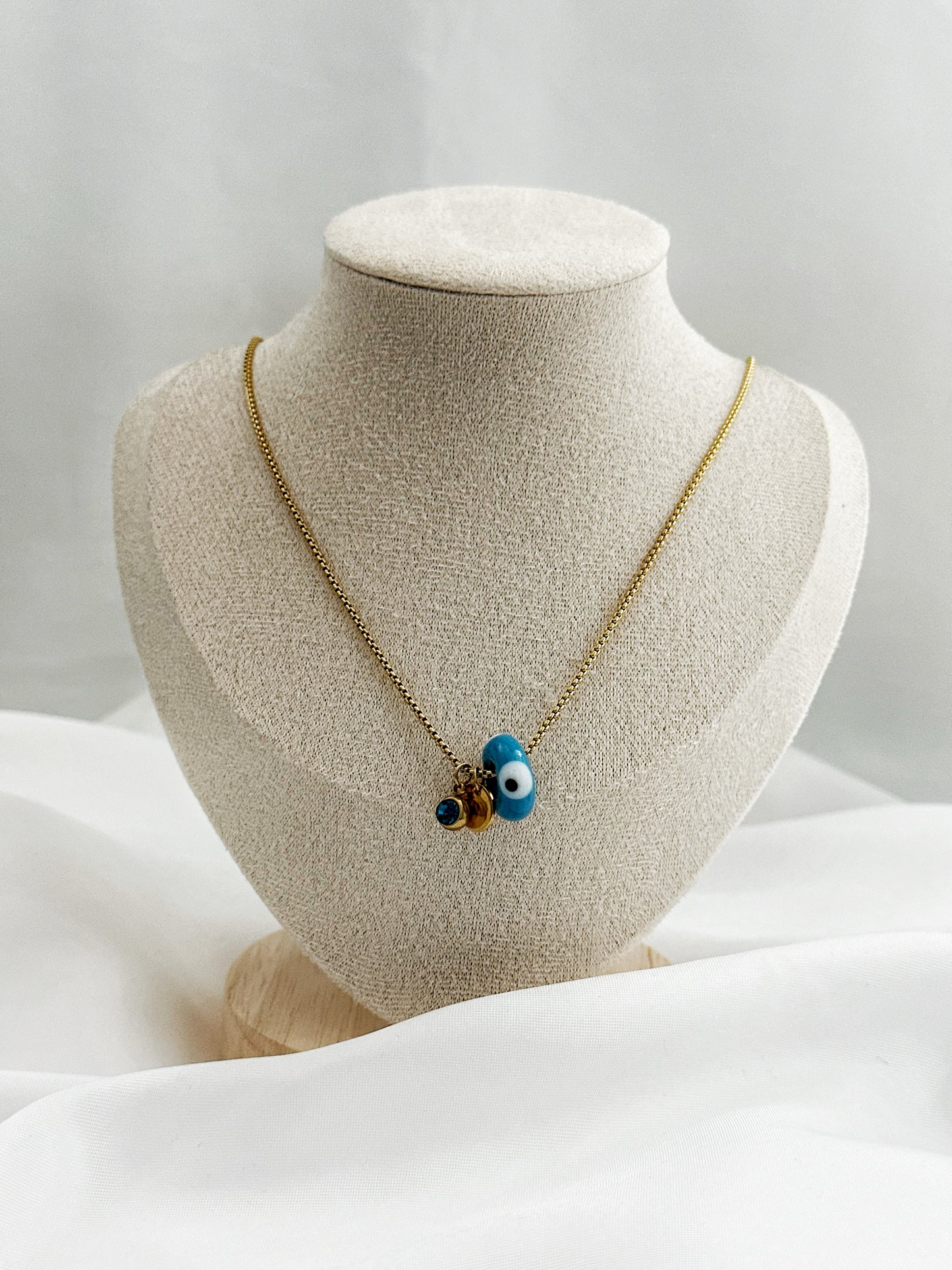 Goldene Edelstahlkette mit drei Anhängern – blauer Glitzerstein, rundes Plättchen und Nazar Auge in Dreiecksform, 45 cm lang