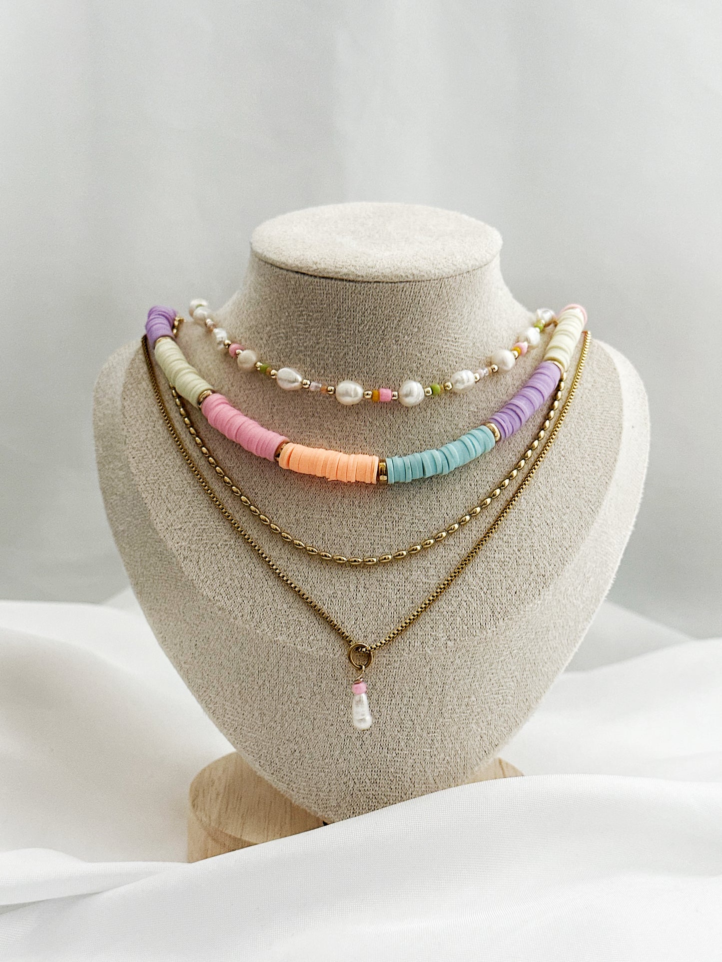 Dreiteiliges Layering-Kettenset mit goldenen Details, Süßwasserperlen und farbigen Akzenten auf Schmuckständer – wählbar in zwei Varianten.