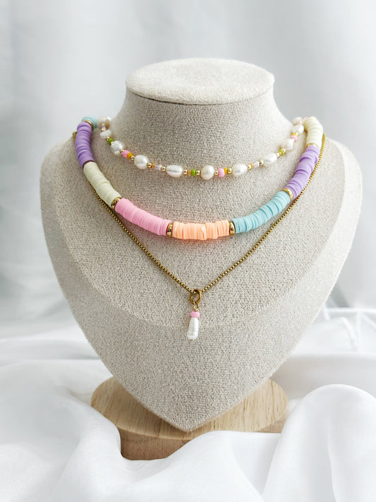Dreiteiliges Layering-Kettenset mit Süßwasserperlen, bunten Perlen und goldenen Details – flach arrangiert auf hellem Untergrund im Sommerstil