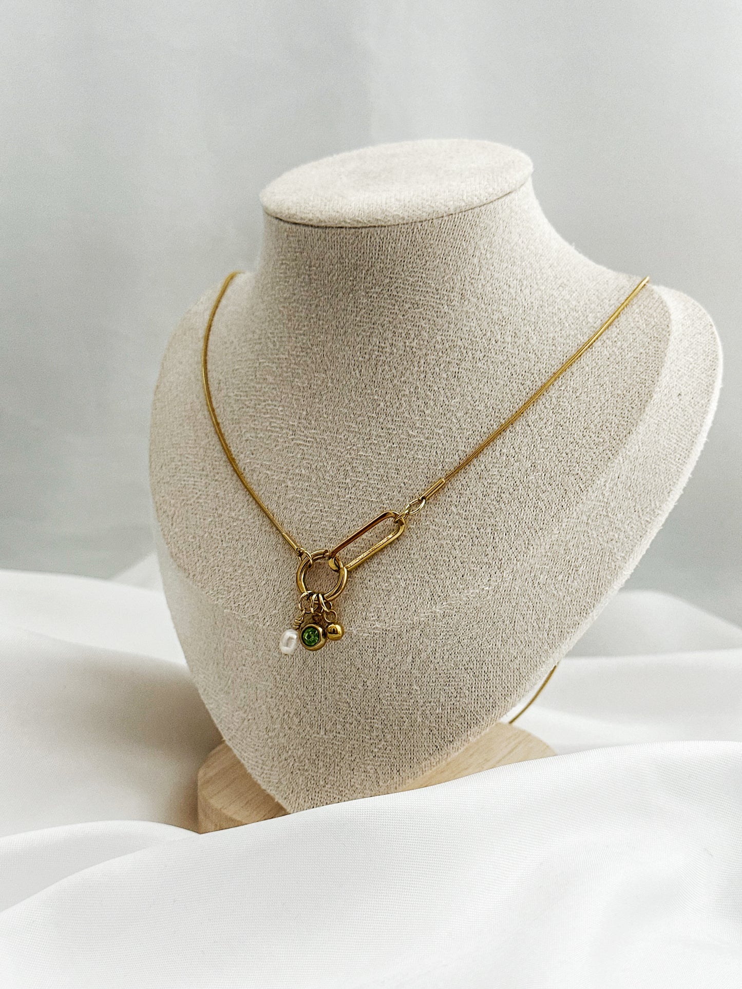 Goldene Edelstahlkette mit Charm-Anhängern – Perle, grüner Zirkonia & Kugel – auf Schmuckbüste präsentiert, 50 cm lang