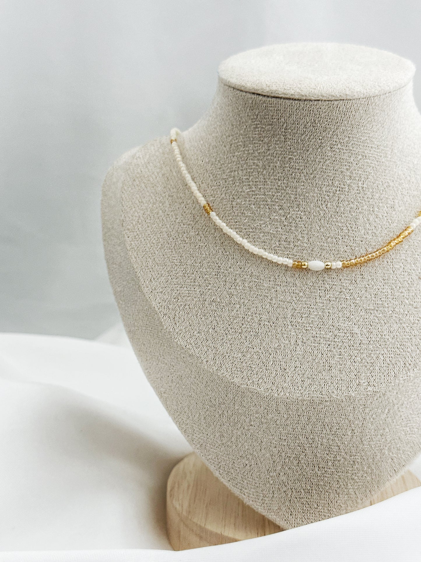 Zweifarbige Perlenkette in Weiß und Gold mit ovaler Perlmuttperle in der Mitte – 40 + 5 cm lang, filigraner Look
