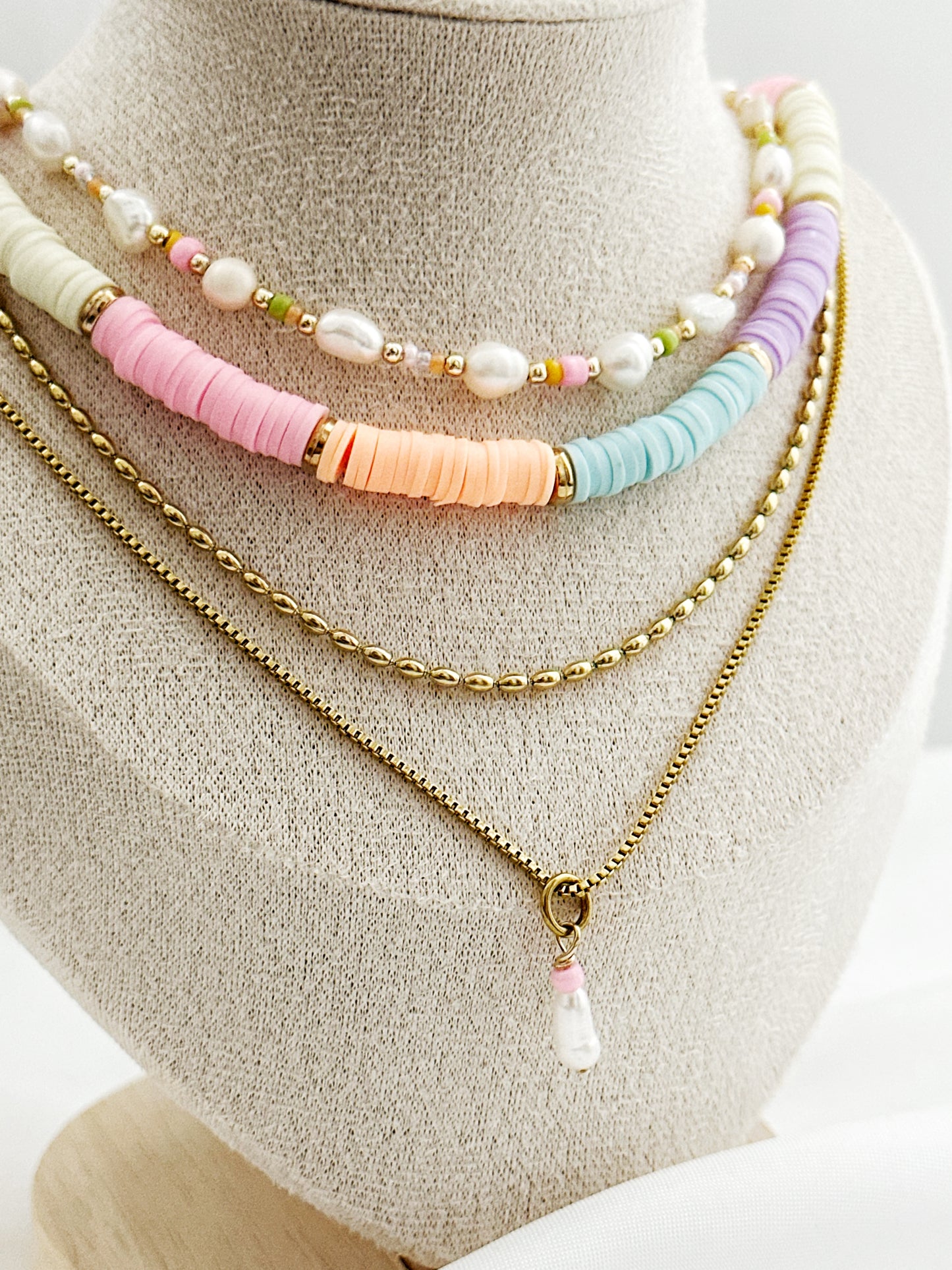 Dreiteiliges Layering-Kettenset mit goldenen Details, Süßwasserperlen und farbigen Akzenten auf Schmuckständer – wählbar in zwei Varianten.