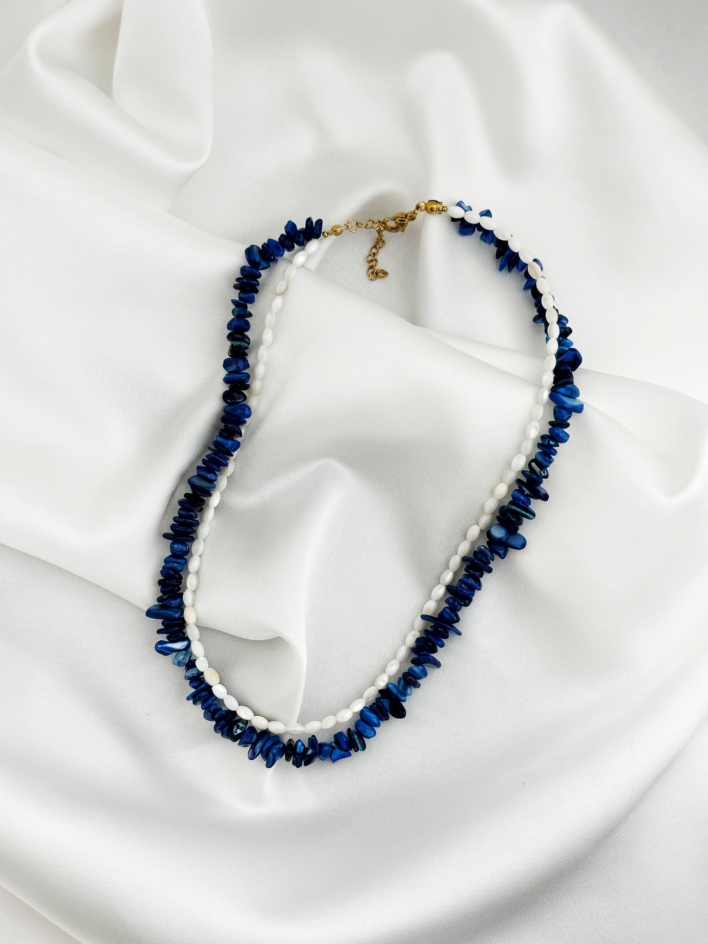 edelstahl layering kette aus lapislazuli-splittern und weißen perlmutt-reisperlen in blau und weiß mit goldenem karabinerverschluss – Luna Mare Kollektion