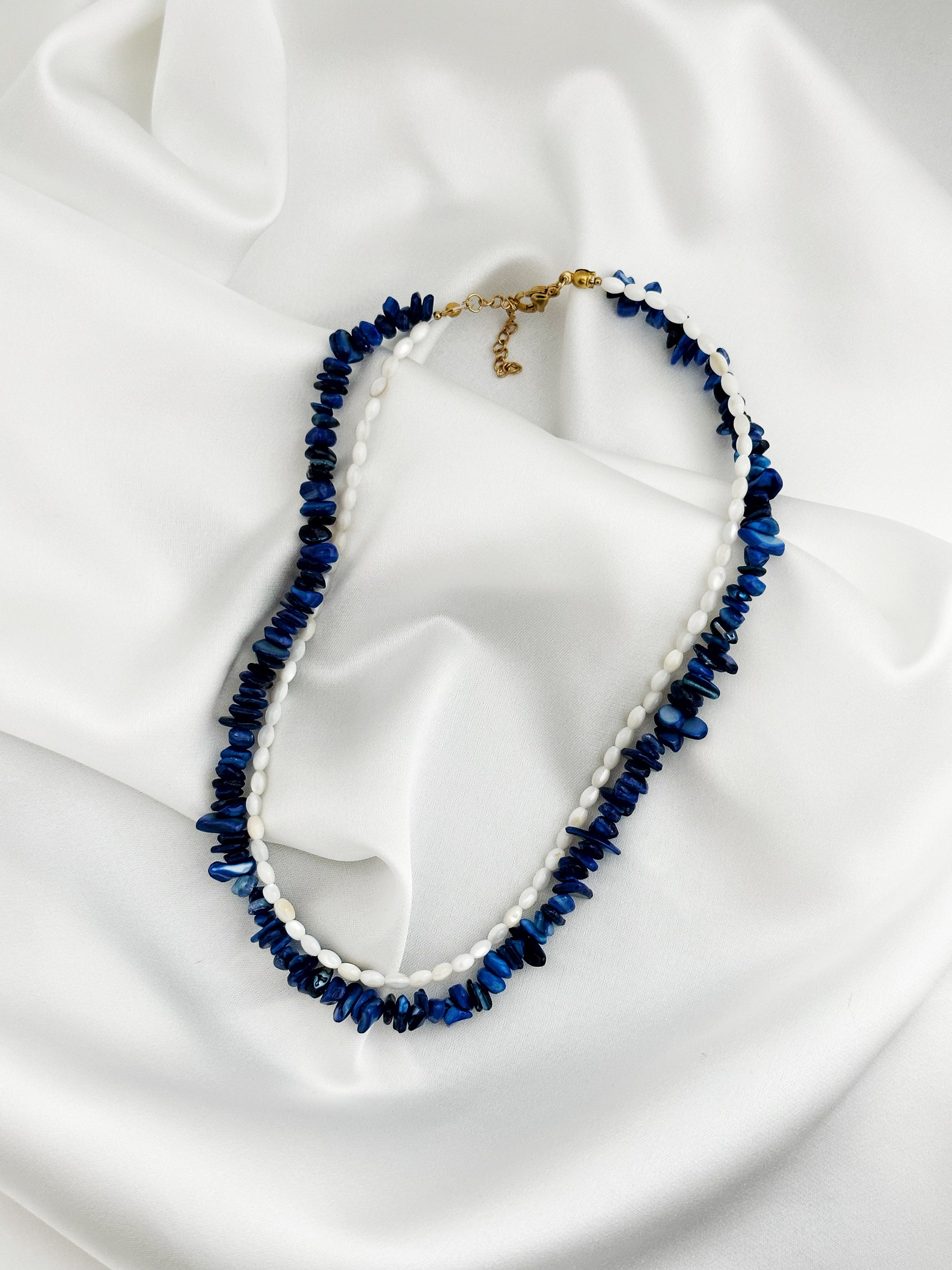 edelstahl layering kette aus lapislazuli-splittern und weißen perlmutt-reisperlen in blau und weiß mit goldenem karabinerverschluss – Luna Mare Kollektion