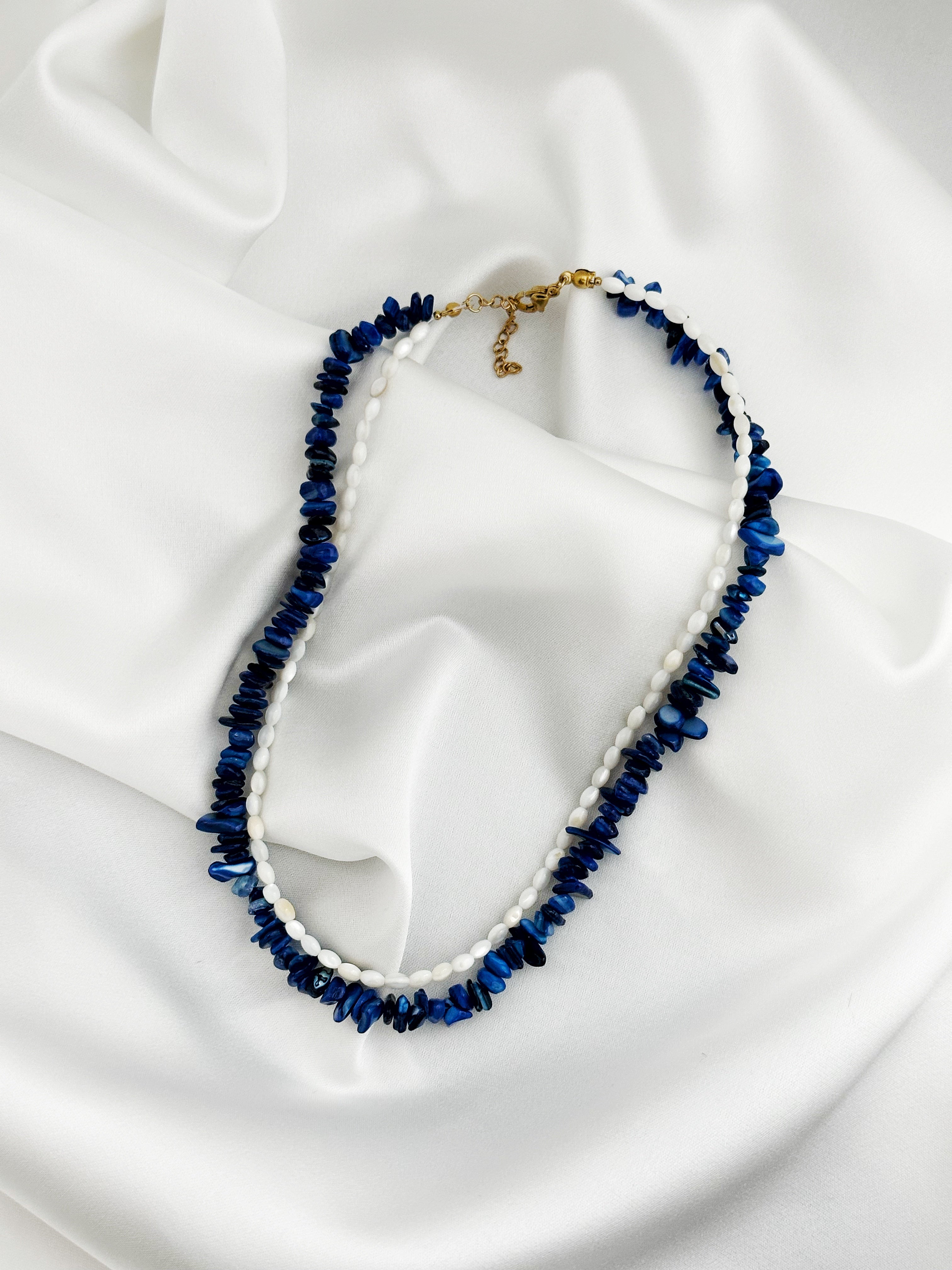 edelstahl layering kette aus lapislazuli-splittern und weißen perlmutt-reisperlen in blau und weiß mit goldenem karabinerverschluss – Luna Mare Kollektion